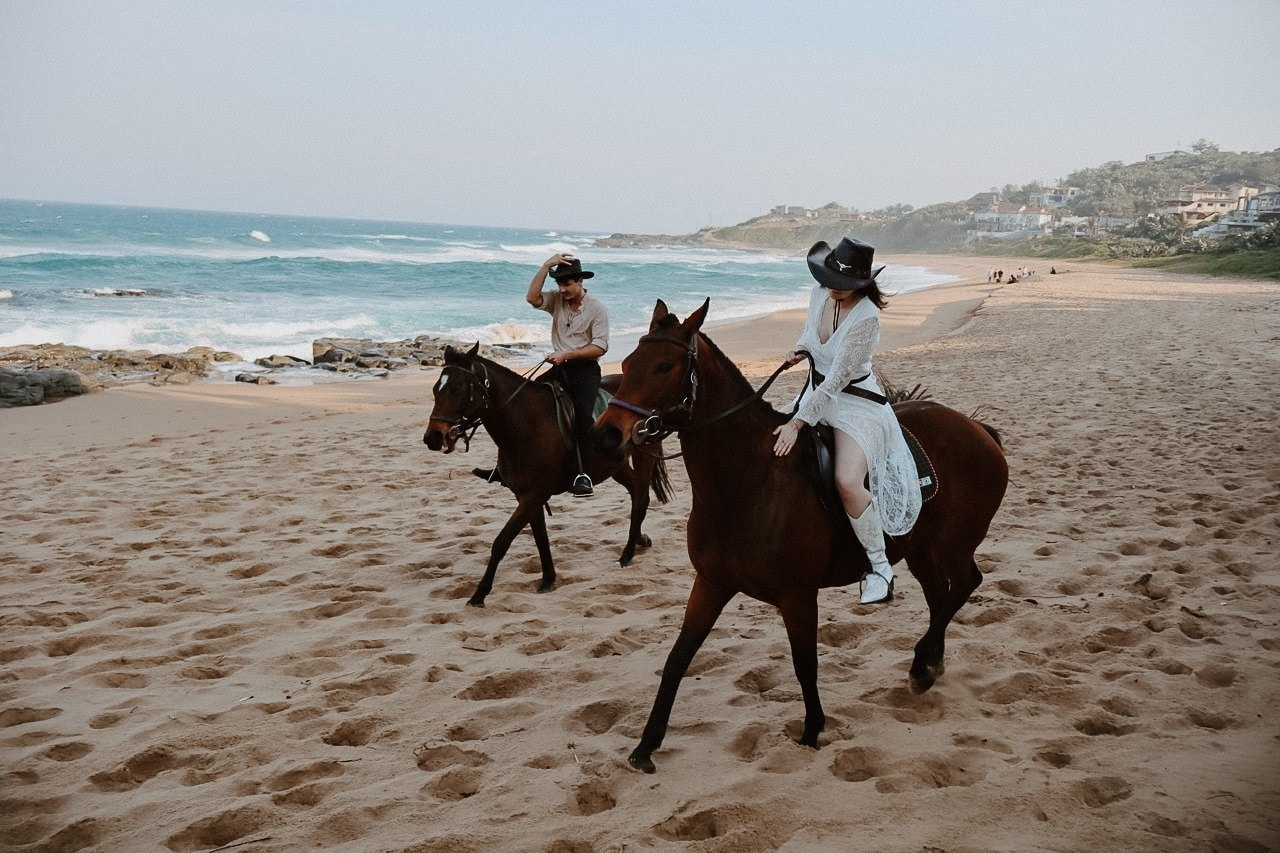 Riders in cowboy hats on a coastal beach